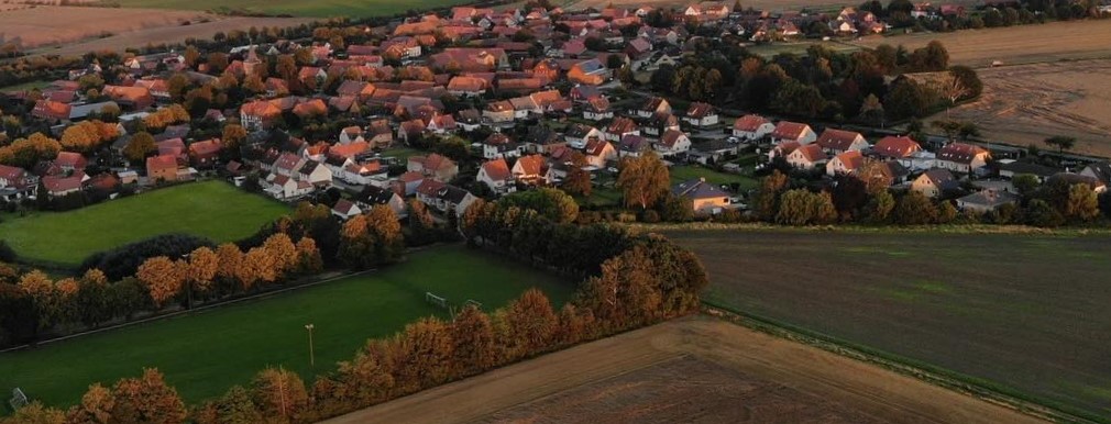 Luftbildaufnahme von Lengde mit Blick über den Sportplatz auf den Dorfkern.